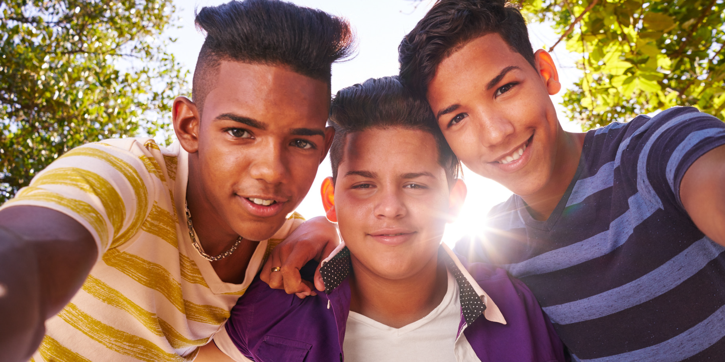 Three children with arms around each other grin down at the camera