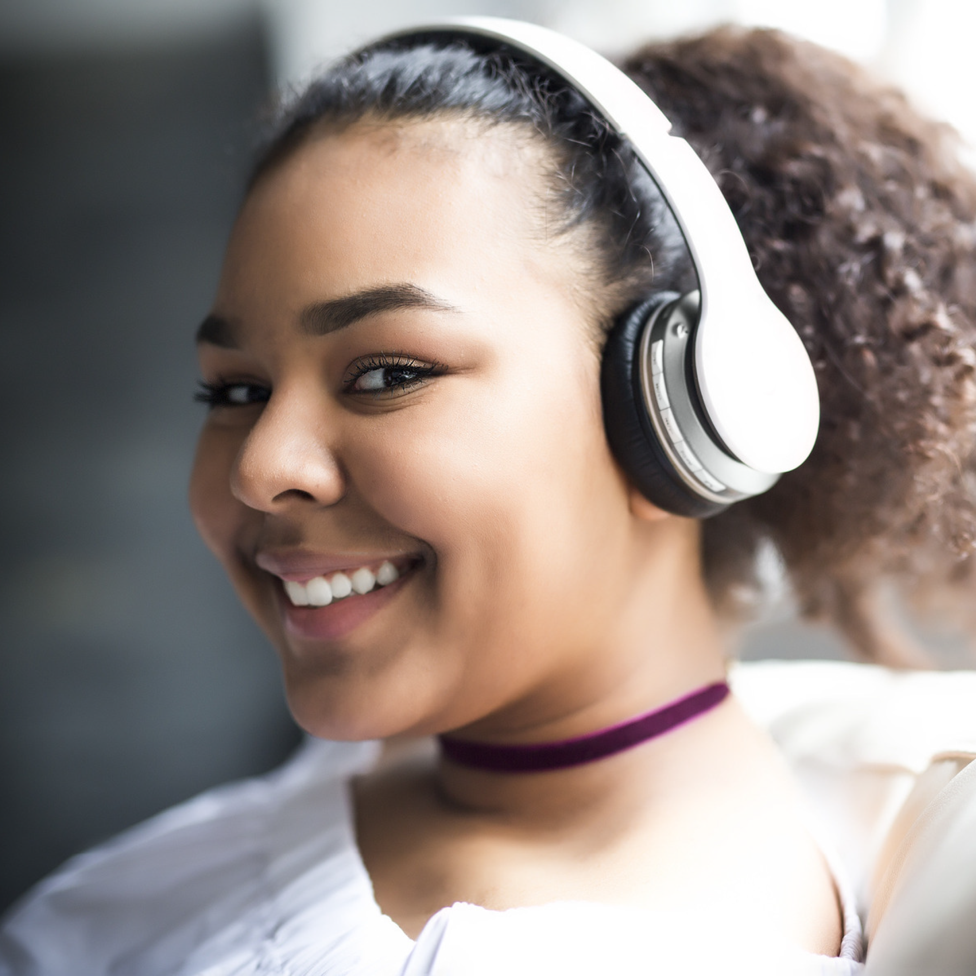 A young woman with headphones smiles happily